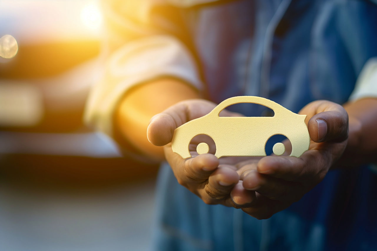 自動車保険の車のアイコンを持つ整備士の手